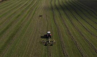 Aerial View of Tractor Tedding Hay in a Green Field photo