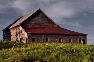 Rustic Wooden Barn With Red Roof in a Rural Setting Under Cloudy Skies in St-Ludger, Quebec, Canada photo