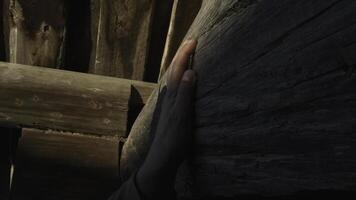 Close up of man hands slowly and timidly touching wooden beam house wall. Media. Concept of returning home after many years. photo