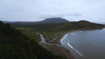 Top view of amazing landscape of mountain coast on cloudy day. Clip. Cinematic landscape of coast with rocky green mountains. Beautiful sea off coast of mountainous north island photo
