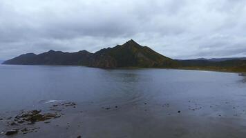 Northern reef coast of sea with mountains. Clip. Top view of reef seascape with mountain views on cloudy day. Cinematic view of coast with mountains on horizon photo