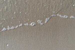The calm wave of the sea with foam on the beach sand photo