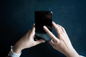 Close up of woman hand using modern smart phone while working in office with computer. and typing a text message on his cell phone. photo