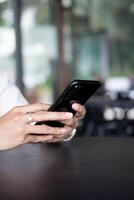 Close up of woman hand using modern smart phone while working in office with computer. and typing a text message on his cell phone. photo