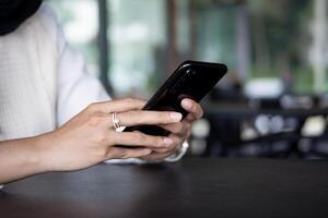 Close up of woman hand using modern smart phone while working in office with computer. and typing a text message on his cell phone. photo