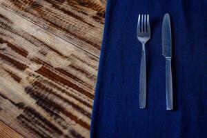 Stylish silver fork and knife resting on a blue cloth, adding elegance to any restaurant table setting. photo