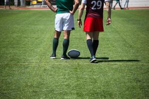 Group of men playing rugby on grass field, tackling and passing ball in action-packed match. photo