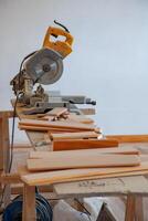 A table saw, stationary, with wooden floorboards positioned for cutting. The scene captures the preparation stage of flooring installation, emphasizing the tools and materials. photo