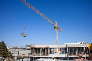 A construction crane hoists materials across a busy worksite, showcasing the dynamic energy and precision involved in modern building projects. photo