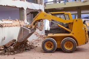 A compact bulldozer clears rubble at a renovation site, showcasing its efficiency and power in handling construction debris. Perfect for illustrating small-scale demolition and construction projects. photo