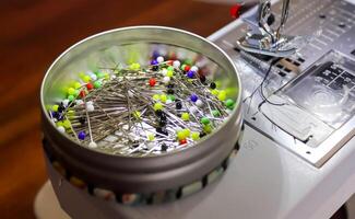 Sewing concept. A can full of colorful pins on a sewing machine photo