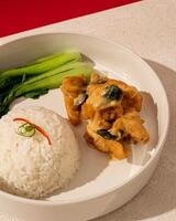 The combination of soft salted egg sauce and crunchy fried chicken is served with warm rice photo