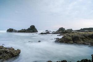 seascape is very beautiful with coral rocks and sea water that looks very soft like cotton at Sawarna Beach, Indonesia. slow shutter speed effect photo