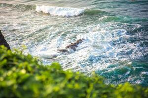 panorama of the scenic view of the beach from a green cliff with very large sea waves. at santolo beach, west java, indonesia photo