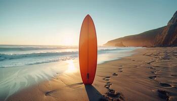 An orange surfboard stands upright on a sandy beach at sunset, with waves rolling in and footprints leading to the water. photo