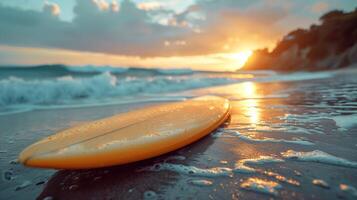 Surfboard on a beach at sunset, with waves in the background. The sky is glowing with warm colors as the sun sets over the horizon. photo