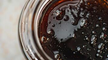 Close-up view of a glass jar filled with dark liquid with bubbles, representing a beverage or syrup. Perfect for food and drink concepts. photo