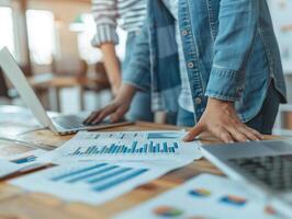 Business professionals reviewing financial charts and data reports on wooden table, teamwork and analytics, collaboration in modern office. photo