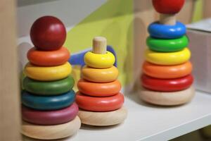 Bright colorful wooden children toy pyramids on a shelf in the shop. Toy shopping photo