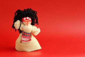 Handmade Motanka doll - traditional ukrainian doll, symbol of fertility and household guardian. Red background with negatice space photo