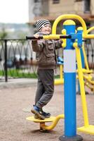 Five year old happy boy working out in the street, in the outdoor gym in the yard on the playground. Boy smiling, making faces photo