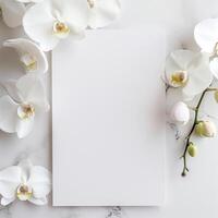 White orchids frame a blank notepaper on marble background. photo