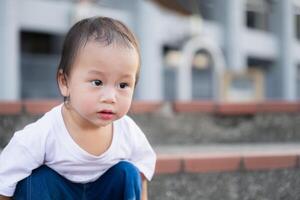 Closeup of a toddler boy sitting and playing in the evening. The cute child was drooling, tears filling his eyes. Asian kids, age 1 and a half. photo