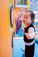 Child playing game of chasing flashing lights, body movement, acumen, observation and agility, learning and muscle development, boy playing happily in playground room, one year and five month old kid. photo