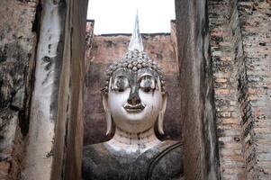An iconic huge Buddha statue inside a roofed building of Wat Si Chum temple located in the North zone of the Sukhothai Historical Park outside the walled city. photo