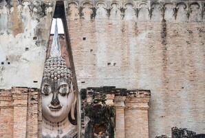 Picturesque view of an iconic huge Buddha statue inside a roofed building of Wat Si Chum temple located in the North zone of the Sukhothai Historical Park outside the walled city. photo