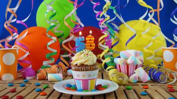 Birthday 58 cupcake with candles burning on rustic wooden table with background of colorful balloons, plastic cups and candies with blue wall in the background photo