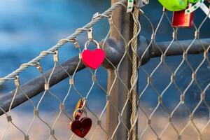 chain link fence with red heart shaped charms hanging from it photo