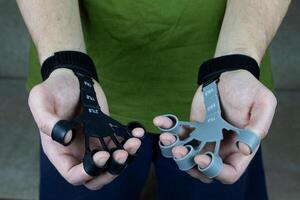 Finger trainer for two hands of man made of silicone with tension force marks for training the strength of the hands and fingers, treating diseases of the joints of the hands photo