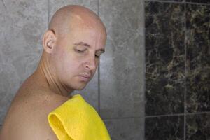 Man rubs his shoulder with washcloth in the shower, care and hygiene of body and skin at home photo
