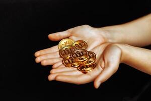 Bitcoins in hand on a black background. photo