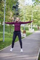 a woman is jumping in the air while wearing a jacket photo