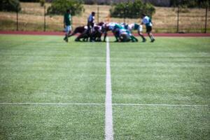 Group of men playing rugby on grass field, tackling and passing ball in action-packed match. photo