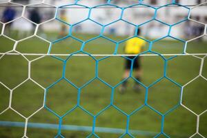 Goalkeeper standing tall, focused, with goal net in foreground. photo