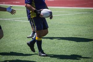 Group of men playing rugby on grass field, tackling and passing ball in action-packed match. photo