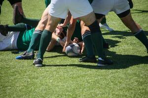 Group of men playing rugby on grass field, tackling and passing ball in action-packed match. photo