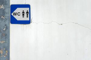 A simple blue and white sign indicating the location of public restrooms in a city. It shows clear, bold lettering with a classic symbol, such as a male and female icon, pointing in a direction. photo