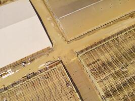 Factory under construction. Aerial drone photo of a factory being built by workers on the edge of Bandung City. Top view of Factory construction