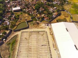 Factory under construction. Aerial drone photo of a factory being built by workers on the edge of Bandung City. Top view of Factory construction