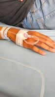 Health and Medical Photography. Photo A patient lies in bed, with his arm infused with nutrients. Functions to maintain electrolyte balance, hydrate the body, restore pH and as a fluid resuscitator.
