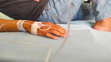 Health and Medical Photography. Photo A patient lies in bed, with his arm infused with nutrients. Functions to maintain electrolyte balance, hydrate the body, restore pH and as a fluid resuscitator.