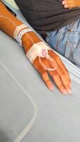 Health and Medical Photography. Photo A patient lies in bed, with his arm infused with nutrients. Functions to maintain electrolyte balance, hydrate the body, restore pH and as a fluid resuscitator.