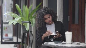 A black woman is getting ready for work in an office uniform in a public downtown area, carrying all her work equipment including a computer and a phone. video