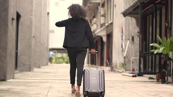 A black woman is getting ready for work in an office uniform in a public downtown area, carrying all her work equipment including a computer and a phone. video