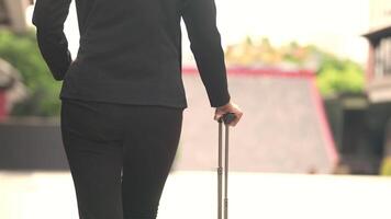 A black woman is getting ready for work in an office uniform in a public downtown area, carrying all her work equipment including a computer and a phone. video