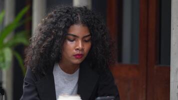 A black woman is getting ready for work in an office uniform in a public downtown area, carrying all her work equipment including a computer and a phone. video